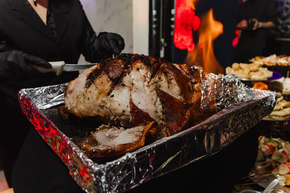 Corte de lechón al momento sobre parrilla con fuego en Eclipse Eventos