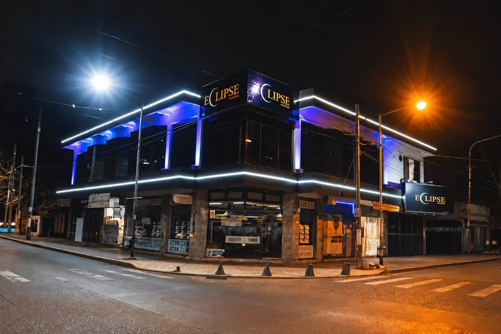Fachada iluminada del salón Eclipse Eventos de noche, con cartel y luces LED azules