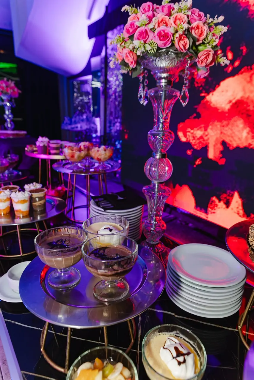 Mesa dulce con postres individuales y centro de rosas en Eclipse Eventos